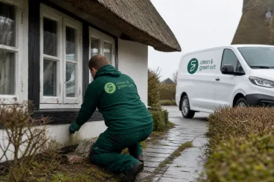 Ein Mitarbeiter prüft ein Reetdachhaus und den nassen Gartenweg auf Sylt.